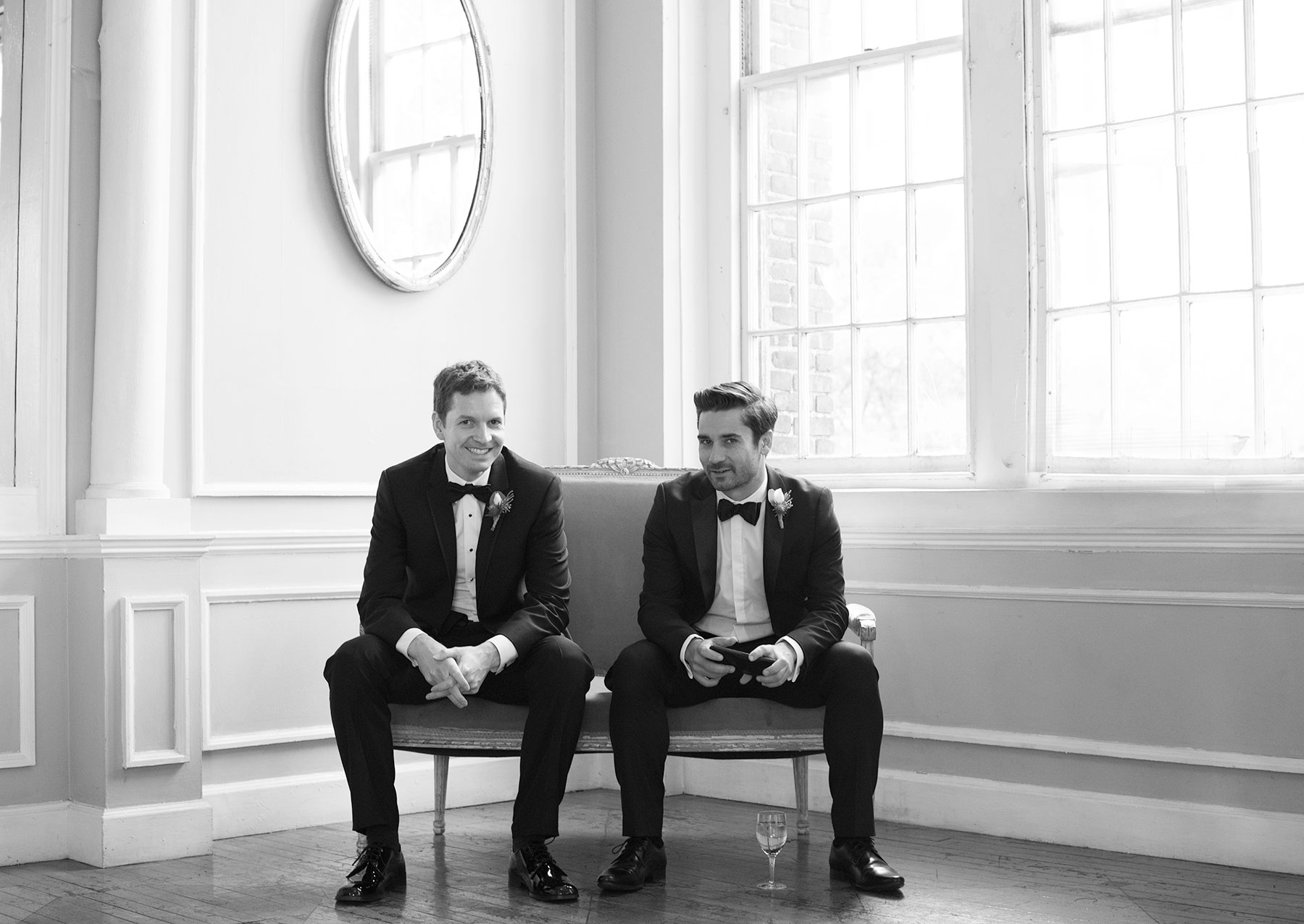 Two elegant grooms sitting in hall at Fall Wedding.