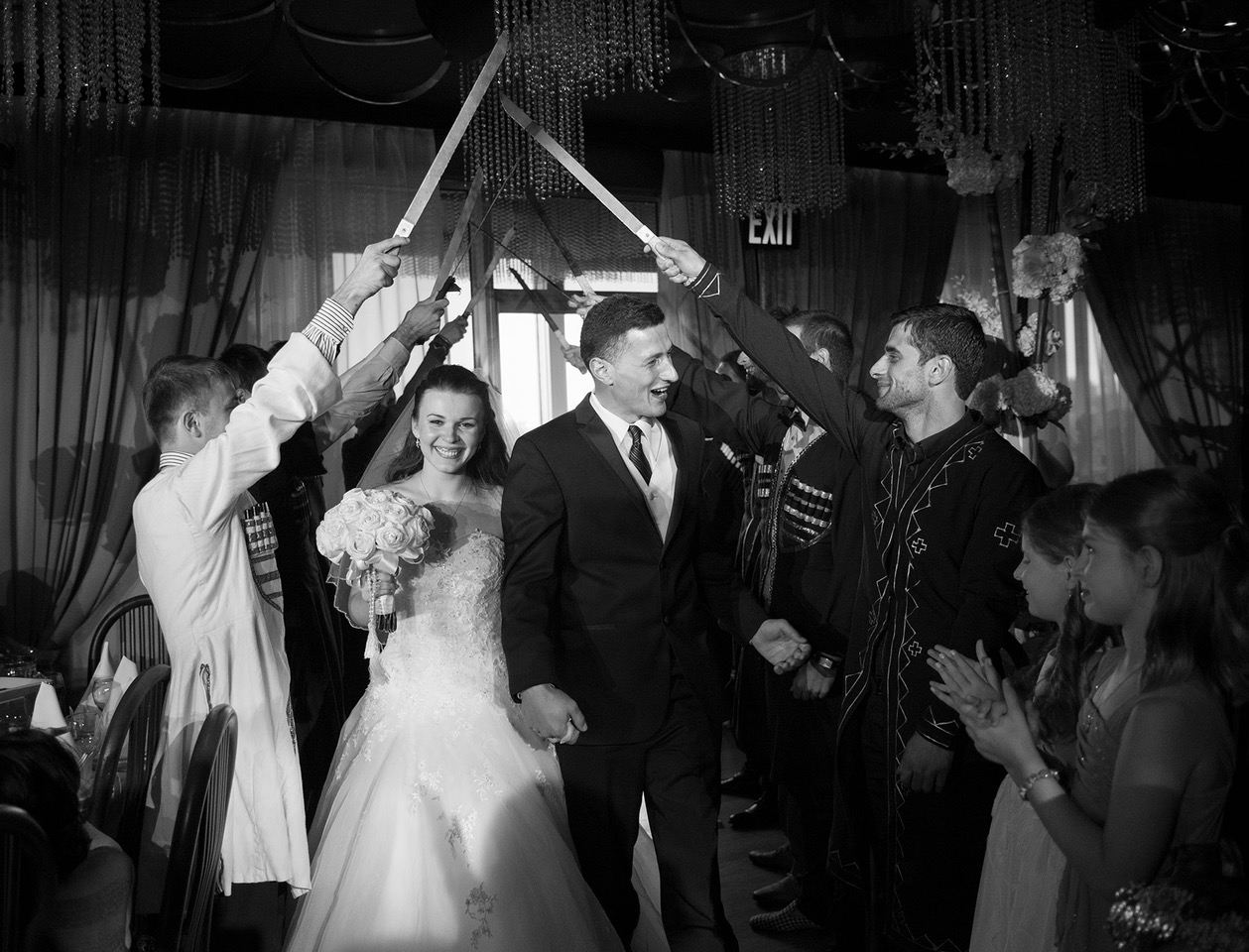 Bride Kate smiling as she passes under swords at wedding
