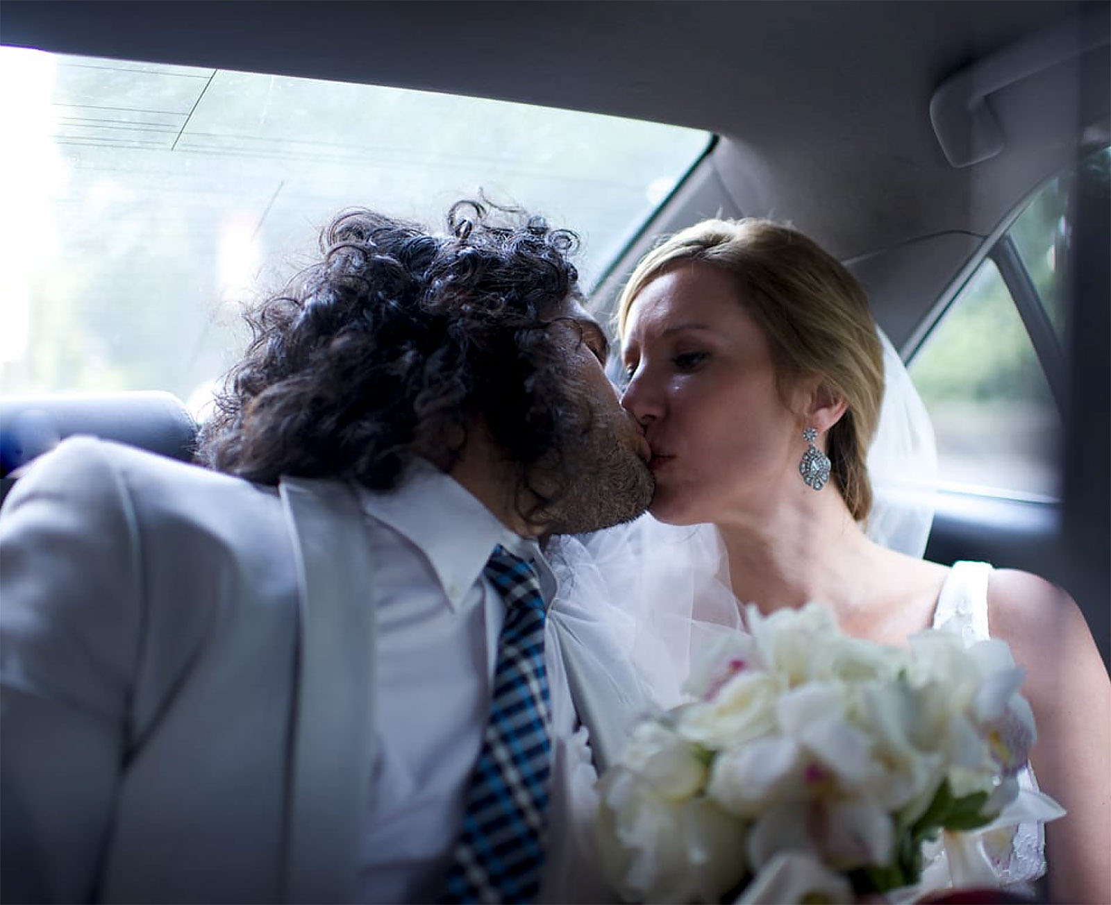A Summer Bride kissing the groom in the backseat of cab