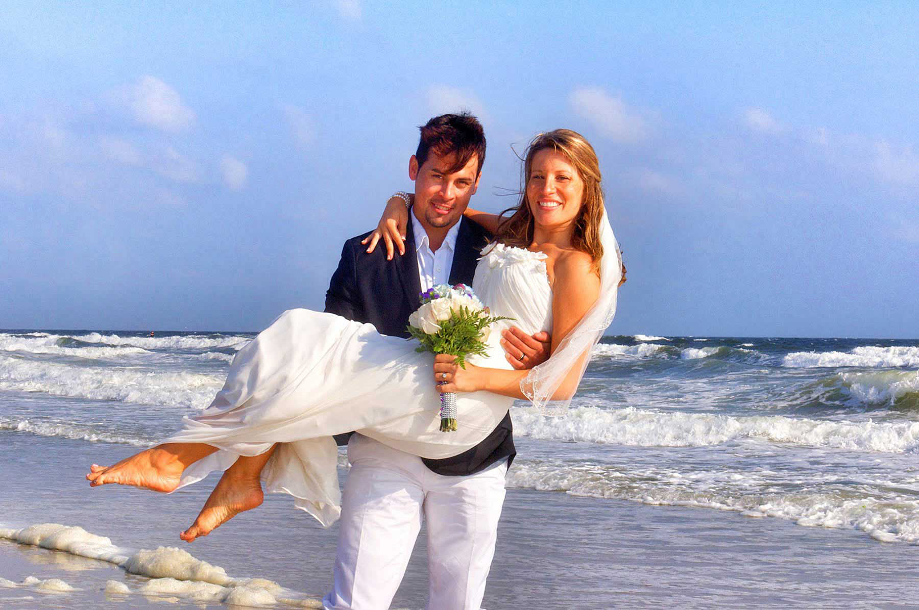 Summer Bride in the arms of Groom at beach wedding