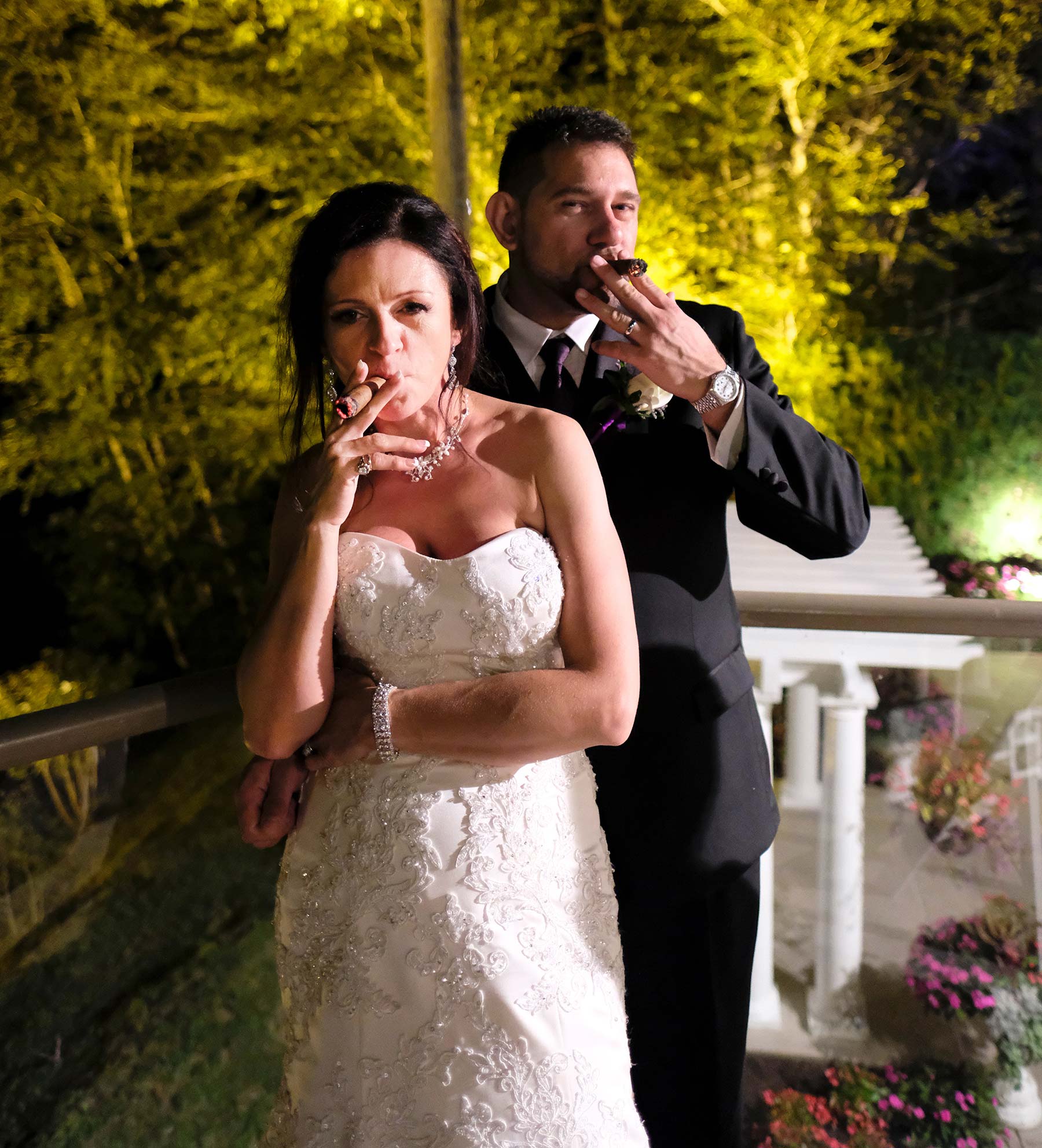 Bride and groom smoking cigar at their wedding